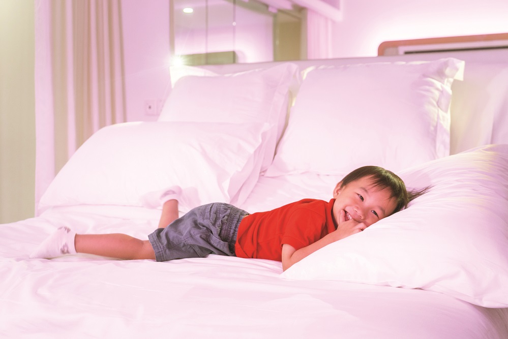 A child lying on a bed in YOTELAIR